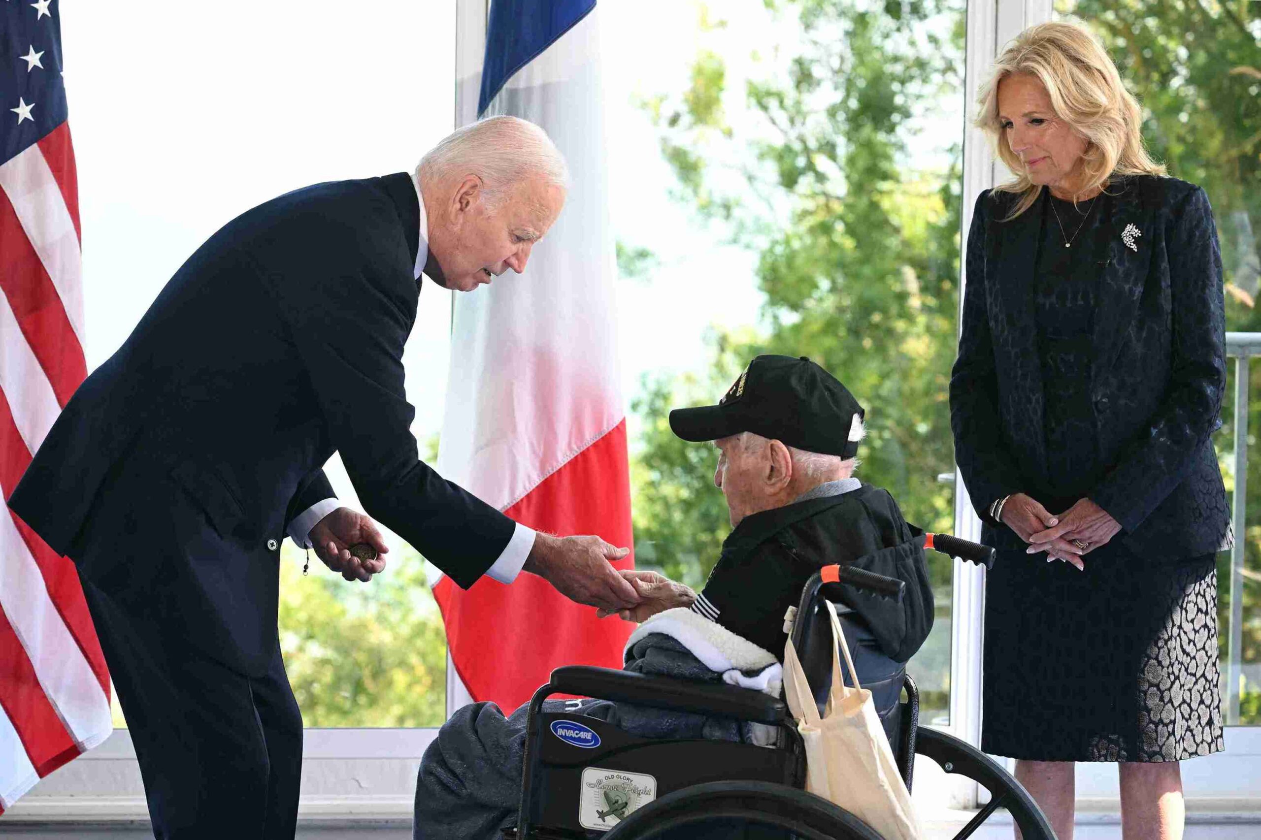 US President Joe Biden shakes hands with a US WWII veteran as US First Lady Jill Biden