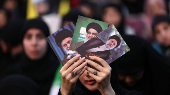 A woman holds pictures of Iran's late president Ebrahim Raisi (R), Lebanon's Hezbollah Secretary General Hassan Nasrallah (C) and Iran's Supreme Leader Ayatollah Ali Khamenei