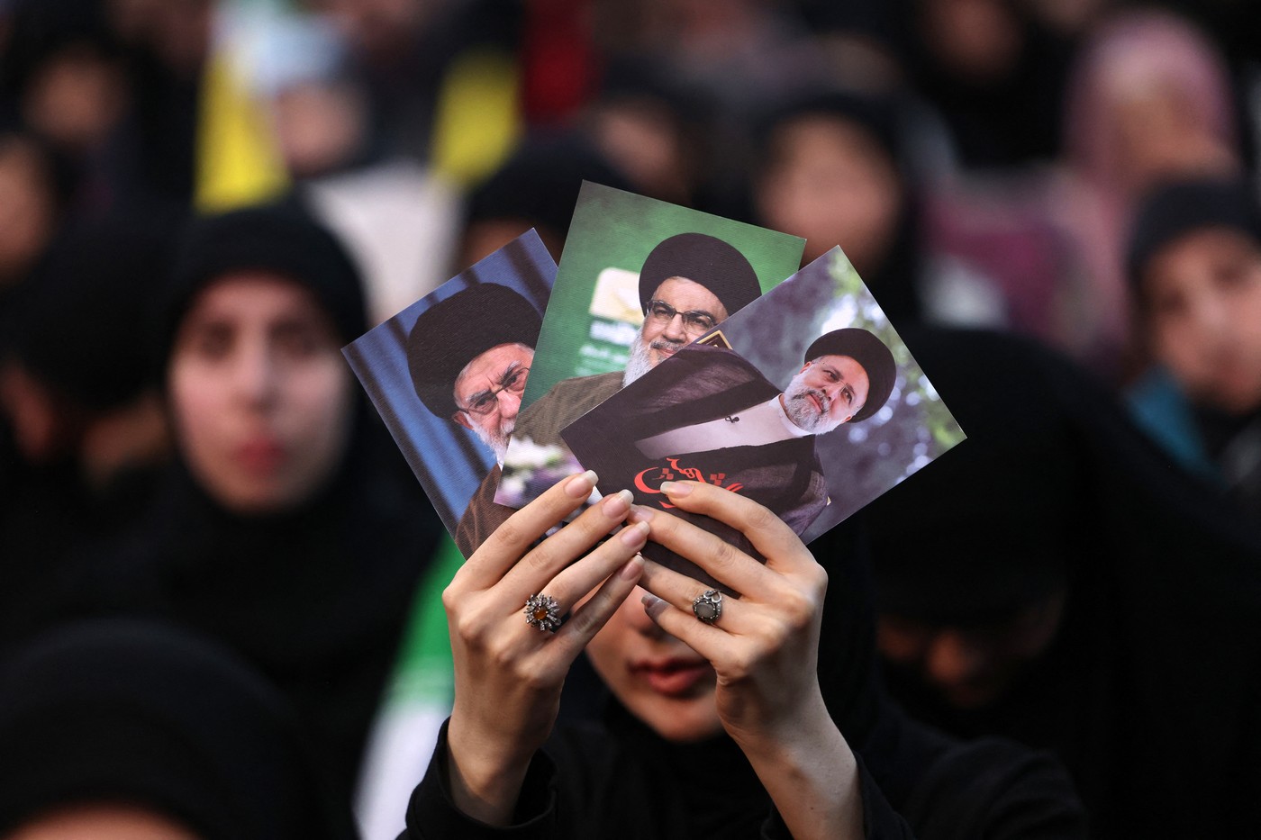 A woman holds pictures of Iran's late president Ebrahim Raisi (R), Lebanon's Hezbollah Secretary General Hassan Nasrallah (C) and Iran's Supreme Leader Ayatollah Ali Khamenei