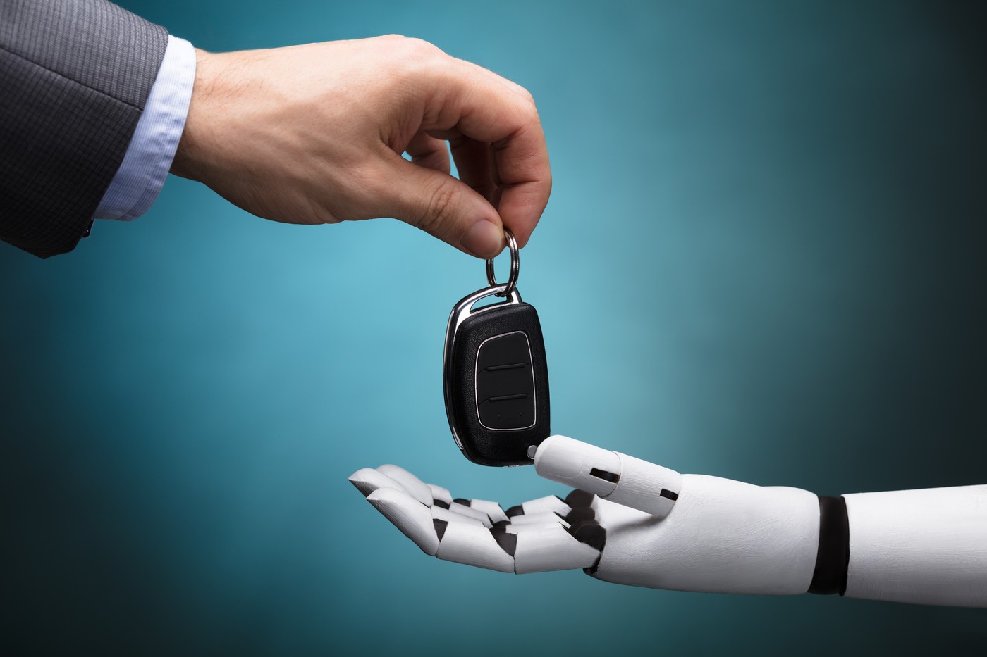 Close-up Of A Businessperson's Hand Giving Car Key To Robot